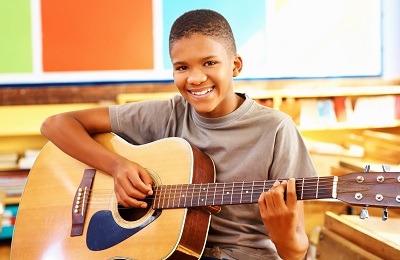 child with a smile holding a
     guitar