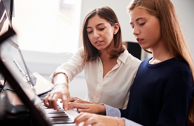 piano teacher and student
  sitting at a piano
